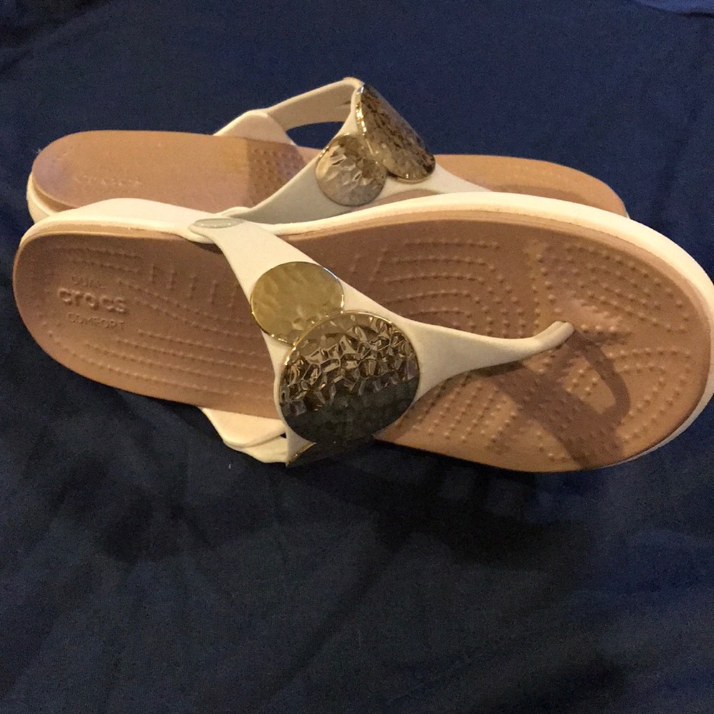 White crocs sandals with gold emblem
